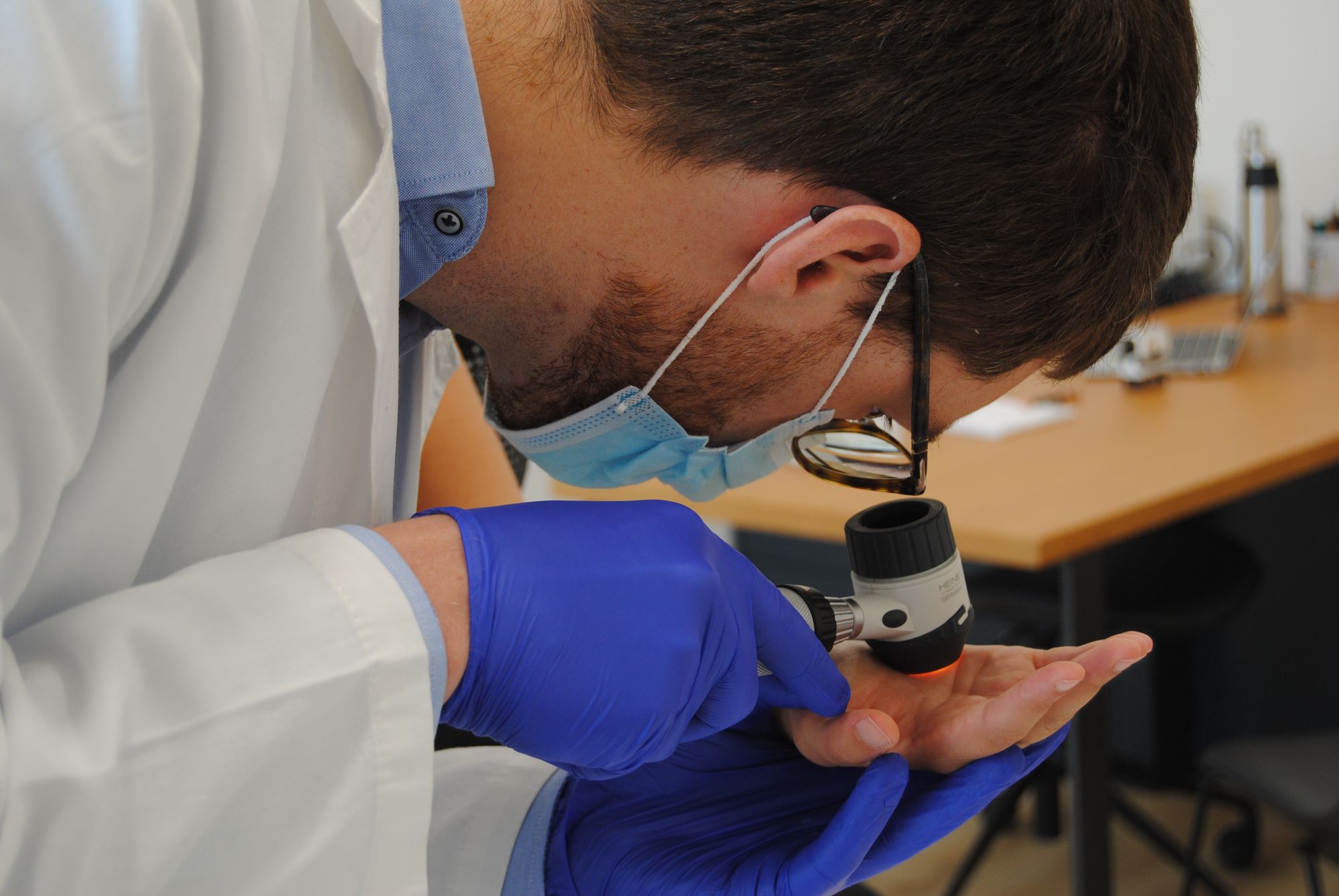 Il Dottor Filippo Bonato che esegue una visita dermatologica alla mano di una paziente